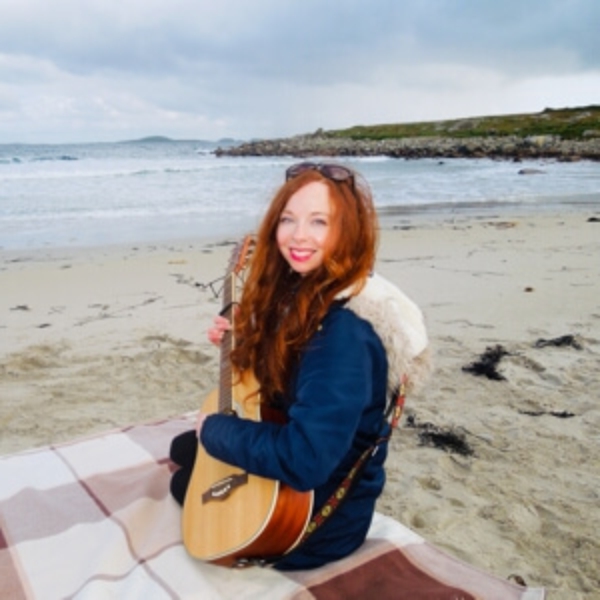 Jo playing guitar on the beach